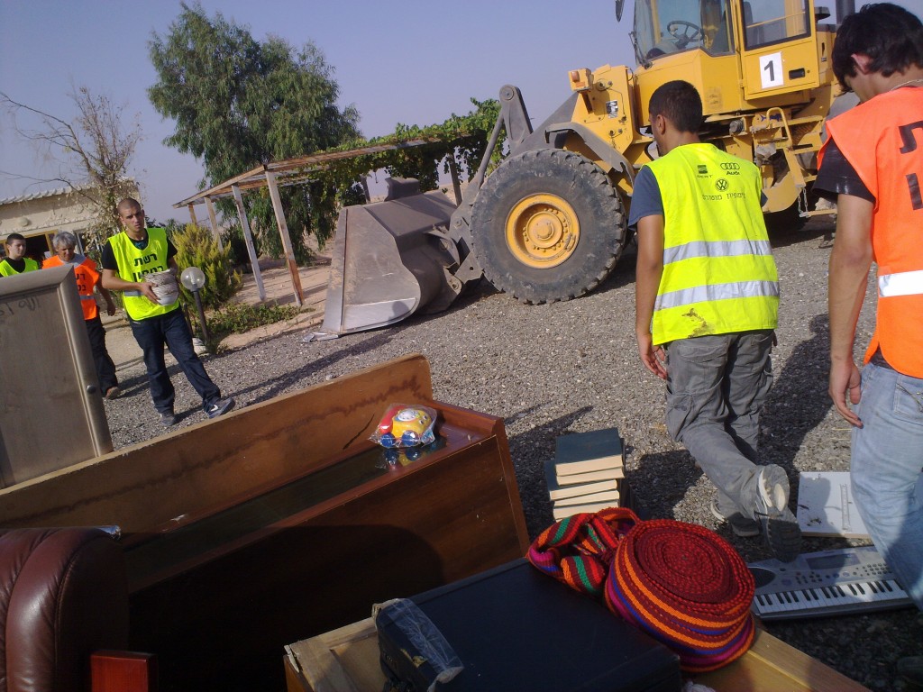 Youth volunteers extract belongings from village homes as bulldozers move in