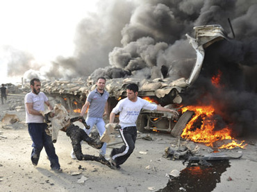 People run carrying a burnt body at the site of an explosion in Damascus May 10, 2012. (Reuters / Sana)
